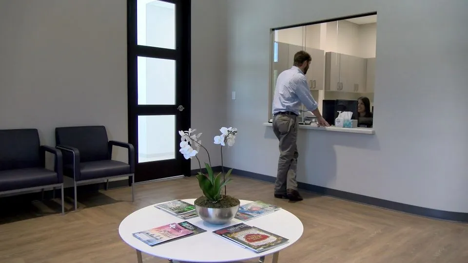 Man at reception desk in waiting area at {PRACTICE_NAME}